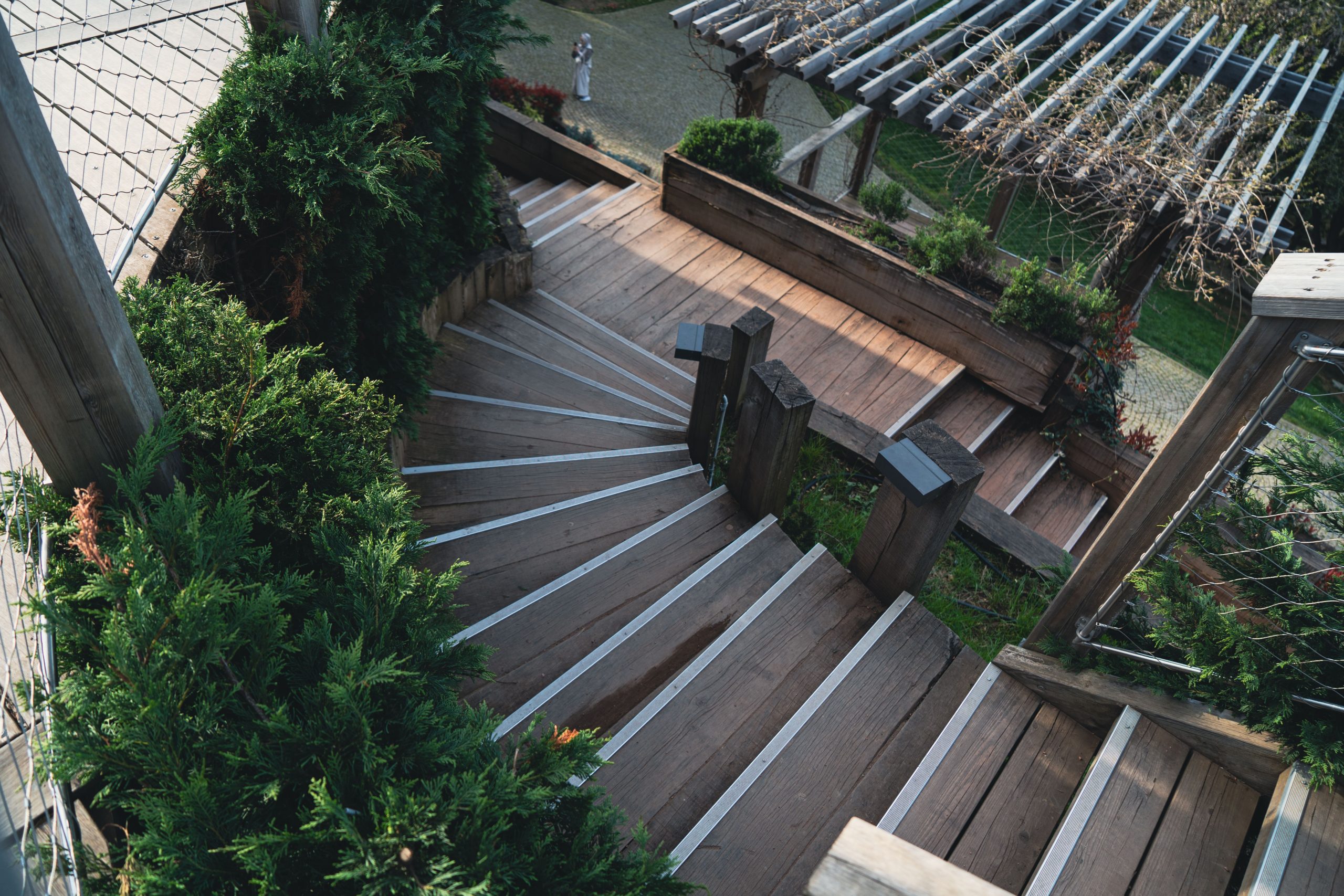 Explore the elegance of a wooden staircase surrounded by lush greenery in an outdoor garden.